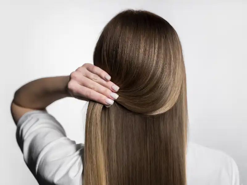 Femme de dos tenant ses beaux cheveux